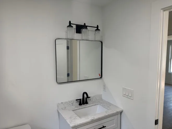 Tub surround & black fixtures — Vanity, mirror & lighting